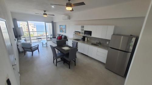 a kitchen and living room with a table and a refrigerator at Hermoso departamento con alberca cerca de la playa in Bucerías