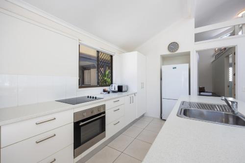 a white kitchen with a sink and a stove at Wolngarin Holiday Resort Noosa in Noosaville
