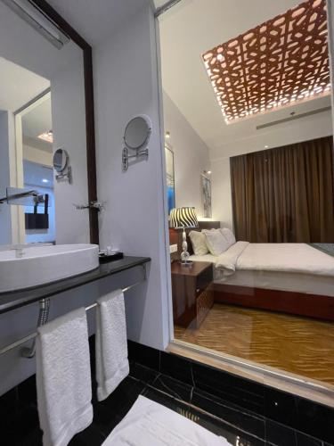 a bathroom with a mirror and a bed and a sink at Empyrean Dhaka City Centre in Dhaka