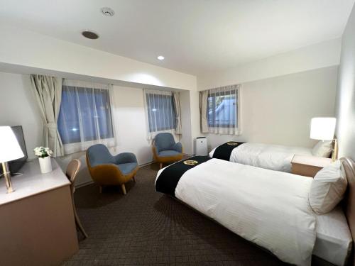 a hotel room with two beds and two chairs at Grand Park Hotel Panex Kimitsu in Kimitsu