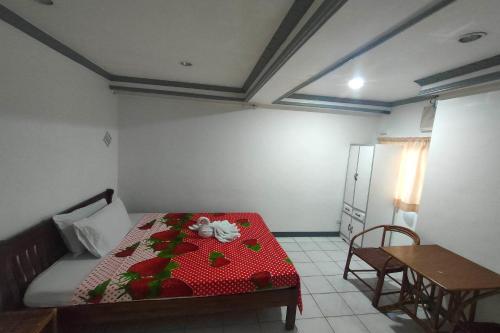 a bedroom with a bed and a table with flowers on it at Istroberi Inn Palawan near Airport in Puerto Princesa City
