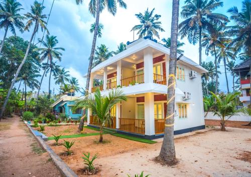 a house with palm trees in front of it at Ocean View Beach Villa Varkala by VOYE HOMES in Varkala