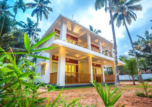 a house on the beach with palm trees at Ocean View Beach Villa Varkala by VOYE HOMES in Varkala