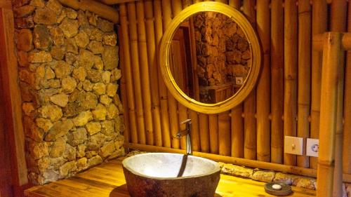 a bathroom with a bath tub with a mirror at Elang Hillside Bamboo Villas in Labuan Bajo