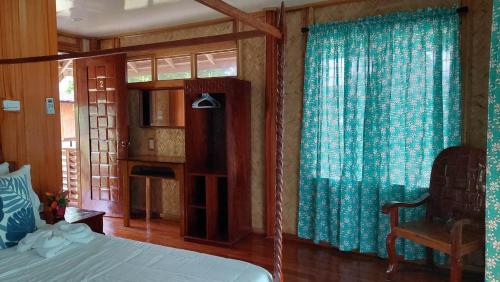 a bedroom with a bed with blue curtains and a chair at La Tranquilidad Twin Beach Resort in Dipnay