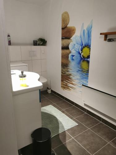 a bathroom with a sink and a painting of a blue flower at Apartment Dreamvalley in Isfjorden
