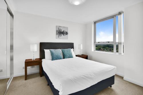 a white bedroom with a large bed and a window at Modern spacious Chatswood Apartment H1016 in Sydney
