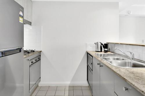 a white kitchen with a sink and a refrigerator at Modern spacious Chatswood Apartment H1016 in Sydney