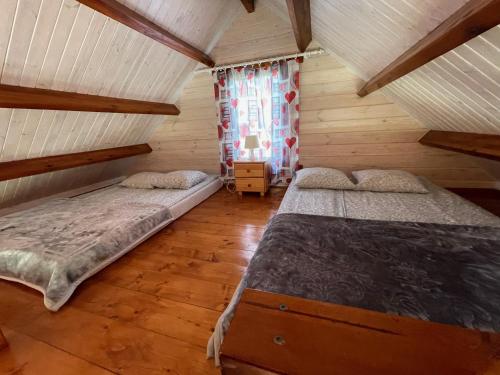 two beds in a room with wooden floors and a window at Osada Turystyczna Miłoszówka in Wąwolnica