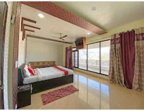 a bedroom with a bed and a large window at Hotel Satkar, Pithoragarh in Pithorāgarh