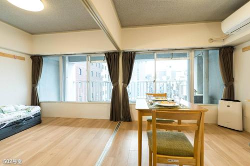 Pokój ze stołem, łóżkiem i oknami w obiekcie Nanei Building - Vacation STAY 03606v w mieście Kagoshima