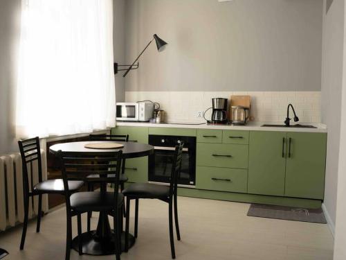 a kitchen with green cabinets and a table and chairs at Comfy apartment in the heart of Ulaanbaatar in Ulaanbaatar