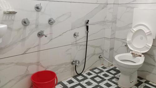 uma casa de banho com um WC branco e um balde vermelho em Hotel shivalay palace em Maheshwar