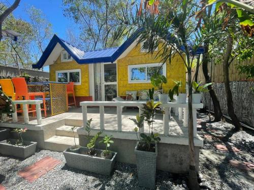 una pequeña casa amarilla con plantas en un patio en Beachfront Glamping with Mini Pool Exclusive Property, en Lingayen