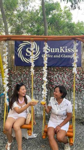 two women sitting on a swing eating food at Beachfront Glamping with Mini Pool Exclusive Property in Lingayen