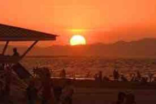a sunset on a beach with a group of people at Beachfront Glamping with Mini Pool Exclusive Property in Lingayen