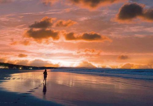 a person walking on the beach at sunset at Beachfront Glamping with Mini Pool Exclusive Property in Lingayen