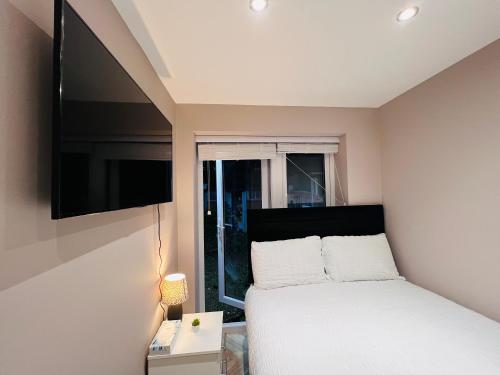 sypialnia z łóżkiem i telewizorem z płaskim ekranem w obiekcie Cozzy w Londynie