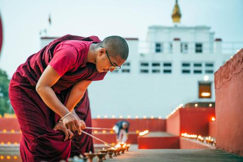 a man lighting candles on top of a building at Hokke Lumbini in Lumbini