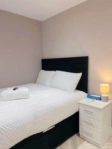a bedroom with a bed with a black headboard and a night stand at LBT Property LTD in London