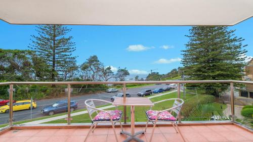 uma varanda com uma mesa e cadeiras e uma rua em 60 Beachpark Apartments - 58 Pacific Drive em Port Macquarie