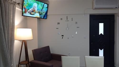 a living room with a tv and a clock on the wall at Angela's Seaside Luxury Flat in Lefkandi Chalkidas