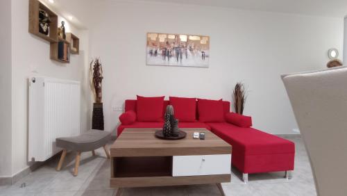 a living room with a red couch and a table at Angela's Seaside Luxury Flat in Lefkandi Chalkidas