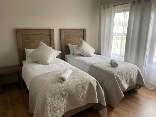 a bedroom with two beds with white sheets and a window at On-Nkwe accommodation in Tierpoort
