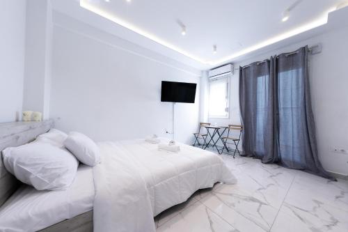 a white bedroom with a bed and a television at Lux studio at French Institute in Thessaloniki