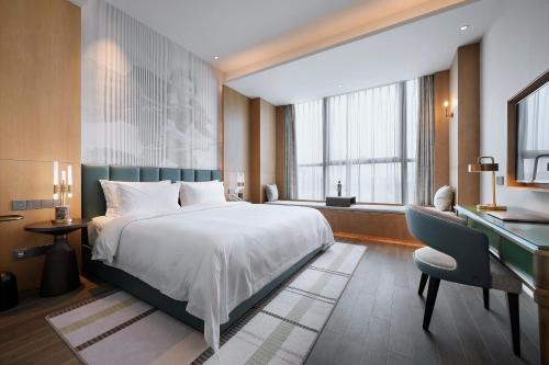 a hotel room with a bed and a desk and a desk at Qingdao Oriental Studio Chuangzhi SSAW Hotel in Qingdao