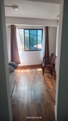 a room with a bed and a chair and windows at Darjeeling Homestay Nyano Ghar in Darjeeling
