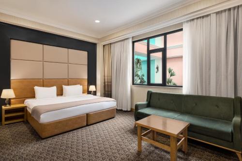 Wyndham Baku في باكو: غرفة فندق بها سرير وأريكة
