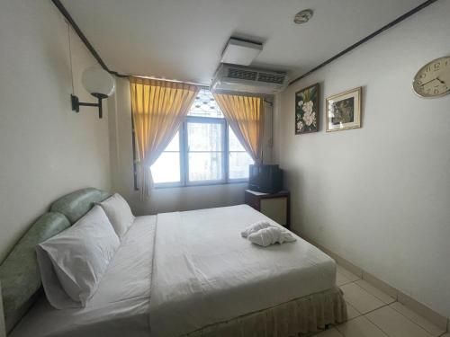 a bedroom with a bed with a clock and a window at Residence Inn Pattaya in Pattaya Central