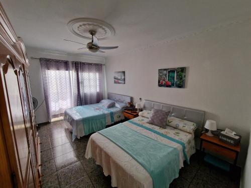 a bedroom with two beds and a ceiling fan at Apartment & Beach breakfast free in Playa del Burrero