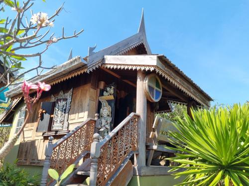 a wooden house with a balcony in a garden at Hello Sichang Bungalow in Ko Si Chang