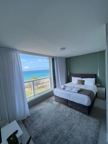 a bedroom with a bed and a view of the ocean at Vacation Apartment By The Beach in Bat Yam