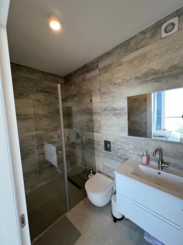 een badkamer met een douche, een toilet en een wastafel bij Vacation Apartment By The Beach in Bat Yam