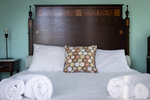 a bed with towels on it with a wooden headboard at Hotel Rural Quinta do Juncal in Serra de El-Rei