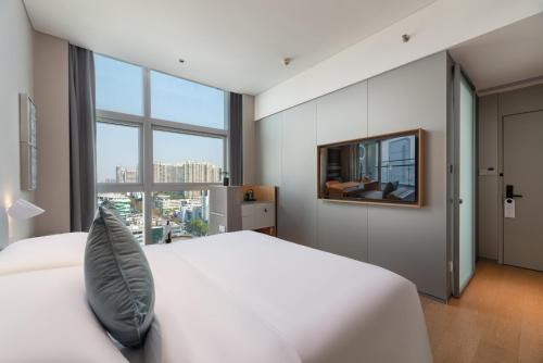 a bedroom with a white bed and a large window at Pagoda Hotel Shenzhen in Shenzhen