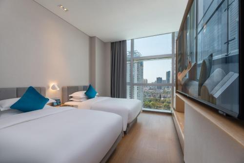 a hotel room with two beds and a large window at Pagoda Hotel Shenzhen Familytrip&BusinessTravel in Shenzhen