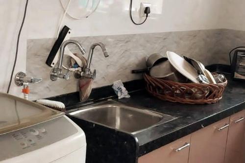 a kitchen with a sink and a basket of dishes at AG House Daman holiday Home apartment in Daman