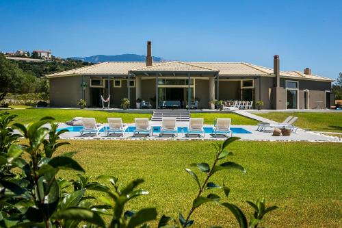 uma casa com um quintal com cadeiras e uma piscina em Villa Katrin Walking Distance to Beach em Kefalonia