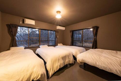 山中湖村にあるtj resort YAMANAKAKO Luxury large villa with Mt. Fuji, Sauna BBQ Max 25のベッド3台と窓2つが備わる客室です。