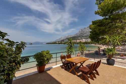 a table and chairs on a balcony overlooking a beach at Beach rooms Riviera - Žuta Kuća in Makarska