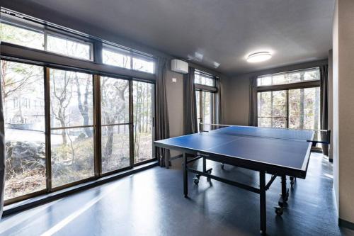 a ping pong table in a room with windows at tj resort YAMANAKAKO Luxury large villa with Mt. Fuji, Sauna BBQ Max 25 in Yamanakako