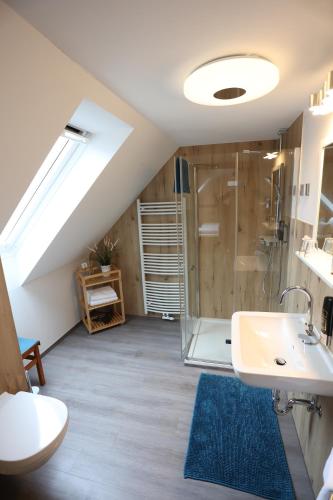 ein Bad im Dachgeschoss mit einem Waschbecken und einer Dusche in der Unterkunft Pension Alte Scheune in Melsungen