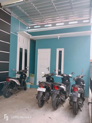 drei Motorräder in einem Raum mit blauer Wand geparkt in der Unterkunft PENGINAPAN HKHAN in Ternate