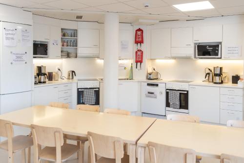 a kitchen with white cabinets and a table and chairs at EC-Hostel in Vaasa