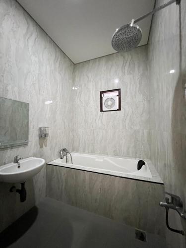 uma casa de banho com uma banheira e um lavatório em Wisma Selma Garuda em Kejayan