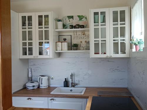 a kitchen with white cabinets and a sink at Apartments Popaj in Komiža